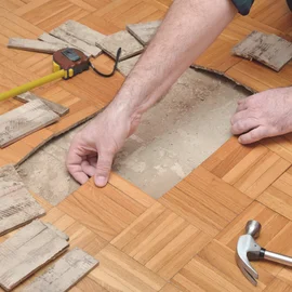Reparatur Parkett, Laminat, Designbelag - Handwerker entfernt beschädigtes Parkett, Erneuerung von Holzfußboden